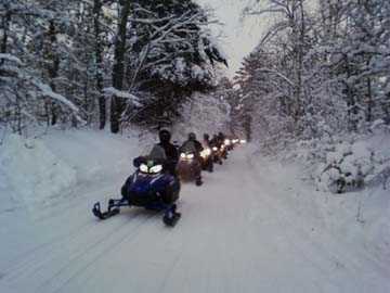 Snowmobilers on a Snowy Wooded Path