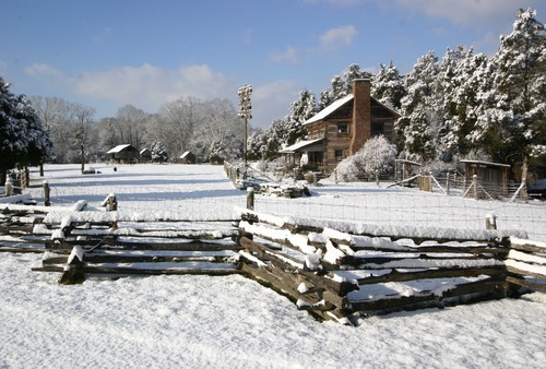 Two-story log house and winter farm landscape